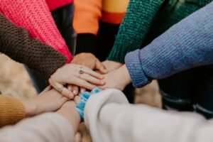 people in a circle puting their hand on top of each other to show unity and support